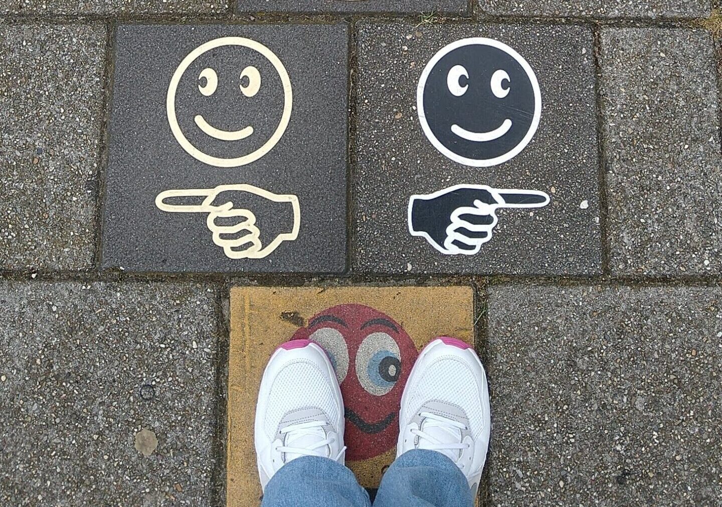 Standing in front of two different smileys faces pointing in two different directions/